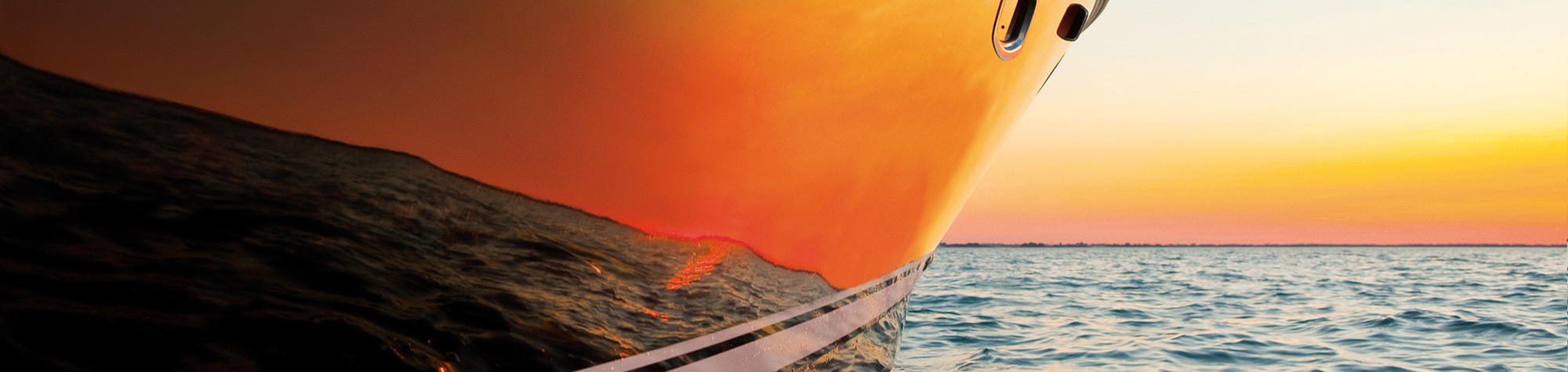 A bright orange sunset, reflected in the hull of a motorboat